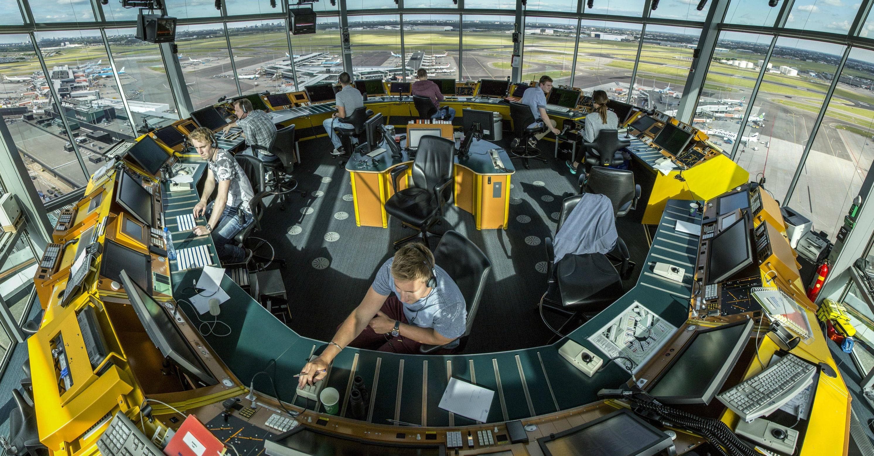 Air traffic controllers inside a tower, focused on screens and instruments, coordinating flights in real time. Coordination holding a complex system together.